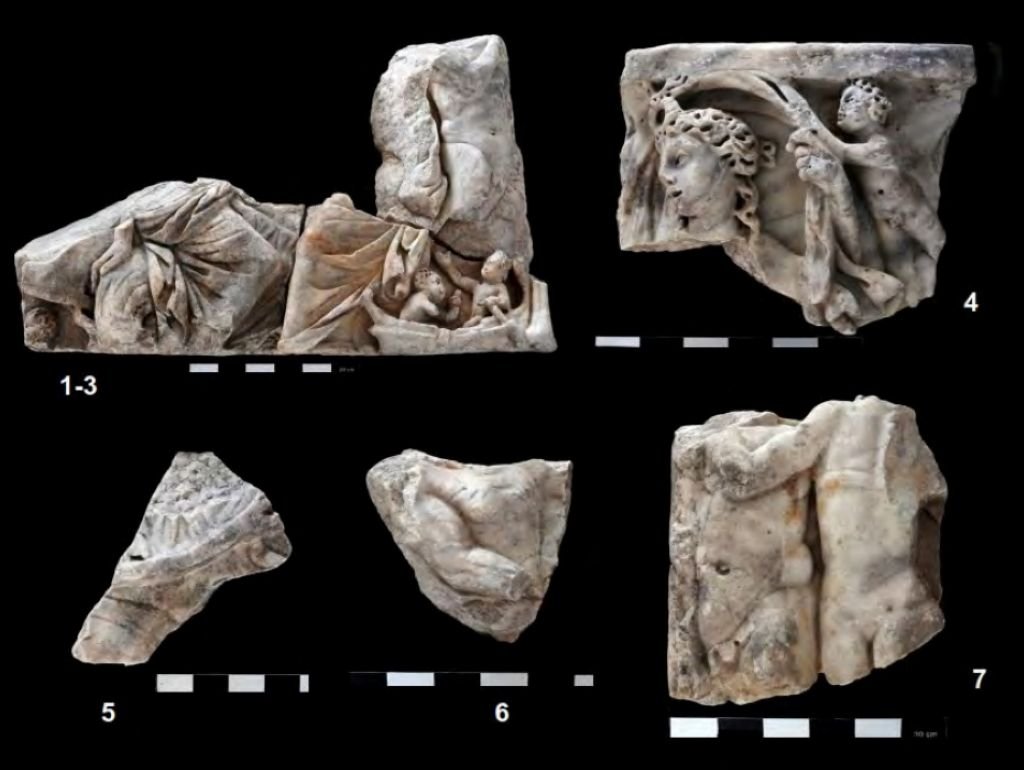 Conjunto de los fragmentos de mármol originales conservados del sarcófago de Medina Sidonia sobre un fondo negro, numerados individualmente y acompañados por escalas de medición arqueológica.