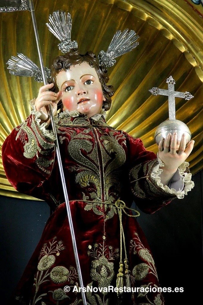 Primer plano de la escultura barroca del Dulce Nombre de Jesús en Jerez, imagen del siglo XVIII vestida con túnica de terciopelo granate bordada en oro, portando el orbe y el estandarte.