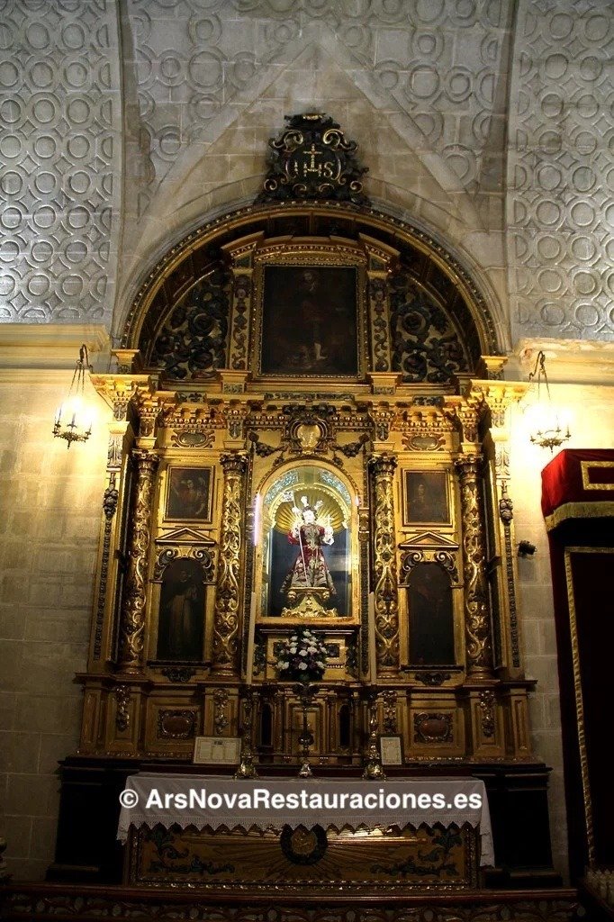 Retablo barroco dorado en la iglesia de Santo Domingo de Jerez con la imagen del Dulce Nombre de Jesús en la hornacina central iluminada, bajo una bóveda de crucería decorada.
