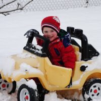 Imagen de niño conduciendo coche de juguete en la nieve