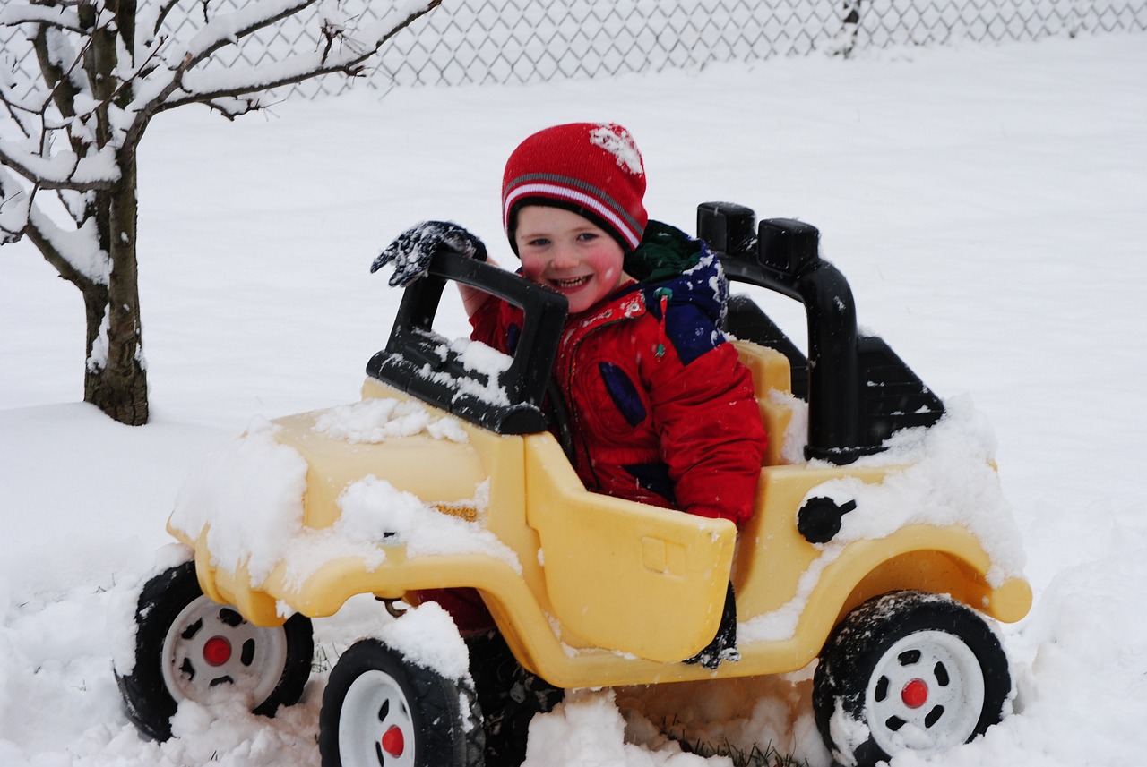 Imagen de niño conduciendo coche de juguete en la nieve