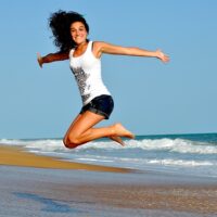 Imagen de mujer saltando contenta en la playa (Pixabay)