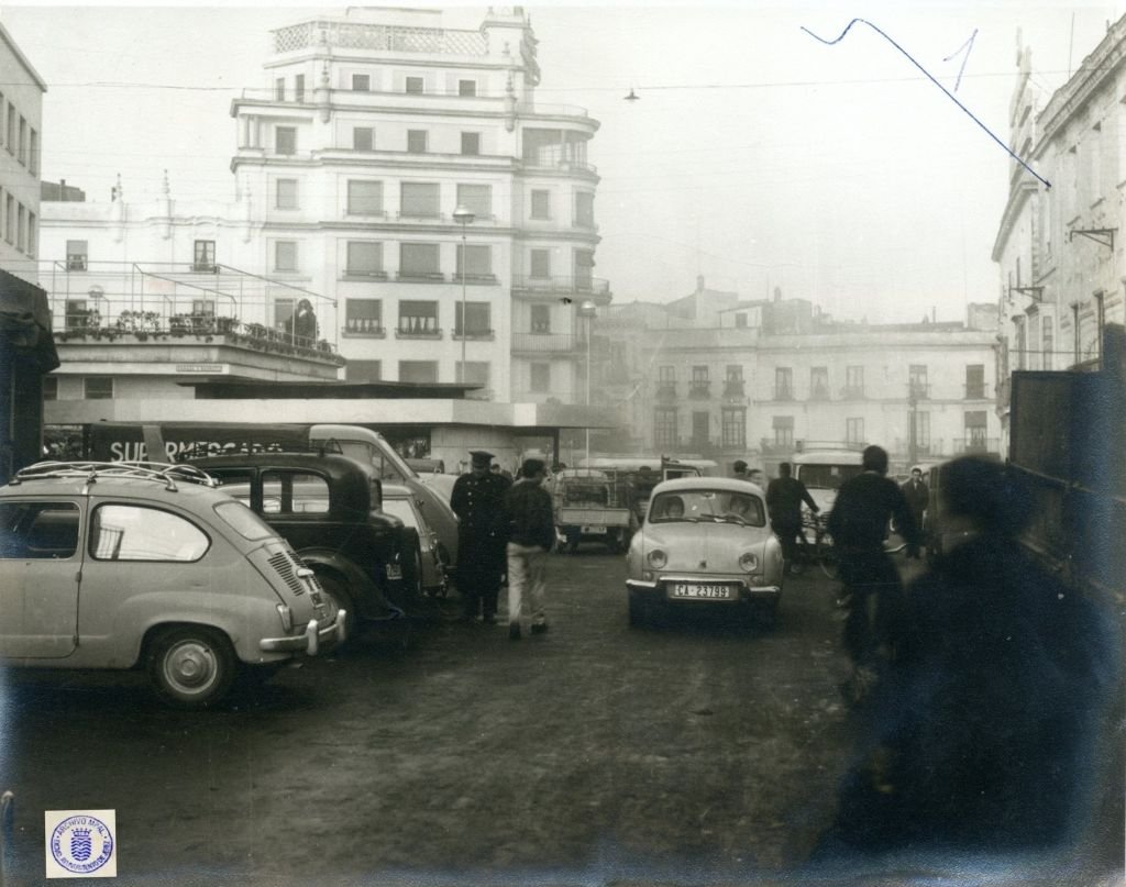 Vista panorámica de la calle Doña Blanca en 1962 con un Seat 600 y un Renault Dauphine en primer plano, destacando al fondo el edificio del Hotel Garage Centro.