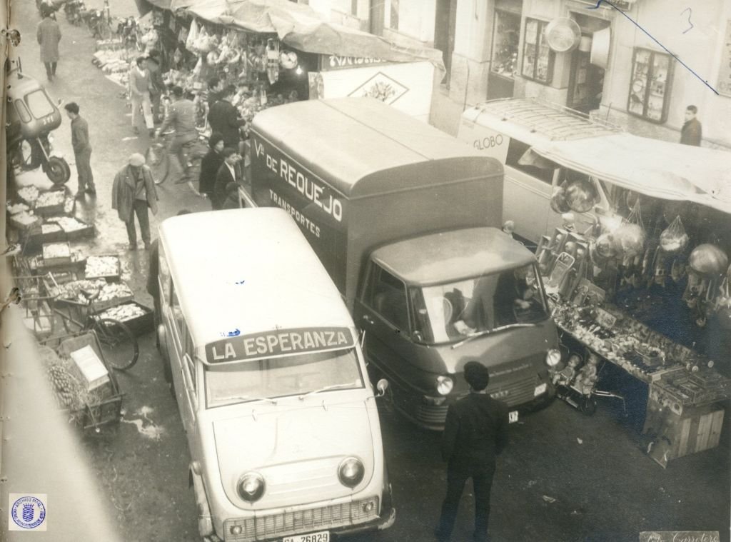 Fotografía en blanco y negro de la calle Doña Blanca en Jerez durante los años 60, mostrando un coche Citroën 11 Ligero avanzando entre una multitud de peatones frente al Mercado de Abastos.