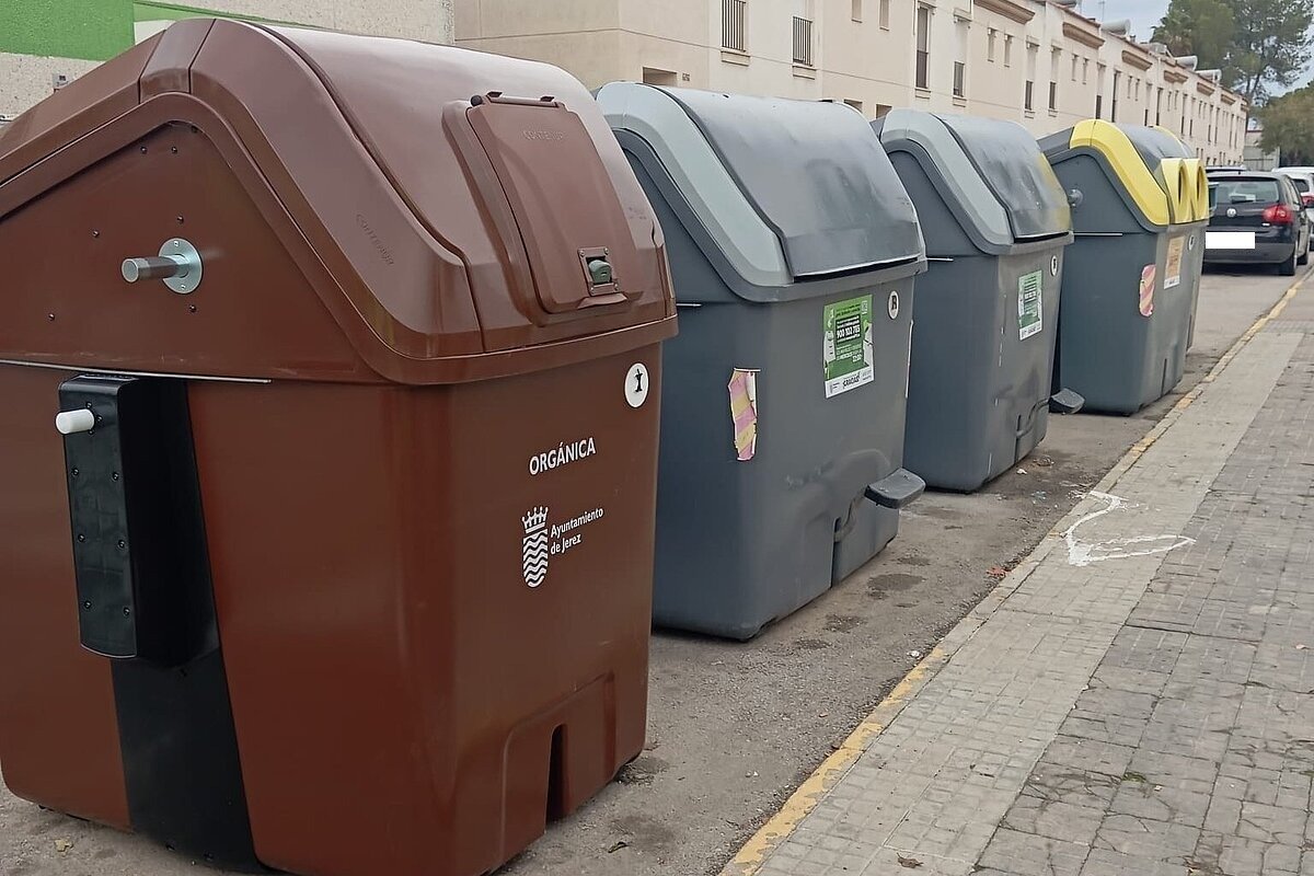 Contenedores de basura de recolección selectiva y materia orgánica del Ayuntamiento de Jerez en una calle residencial.
