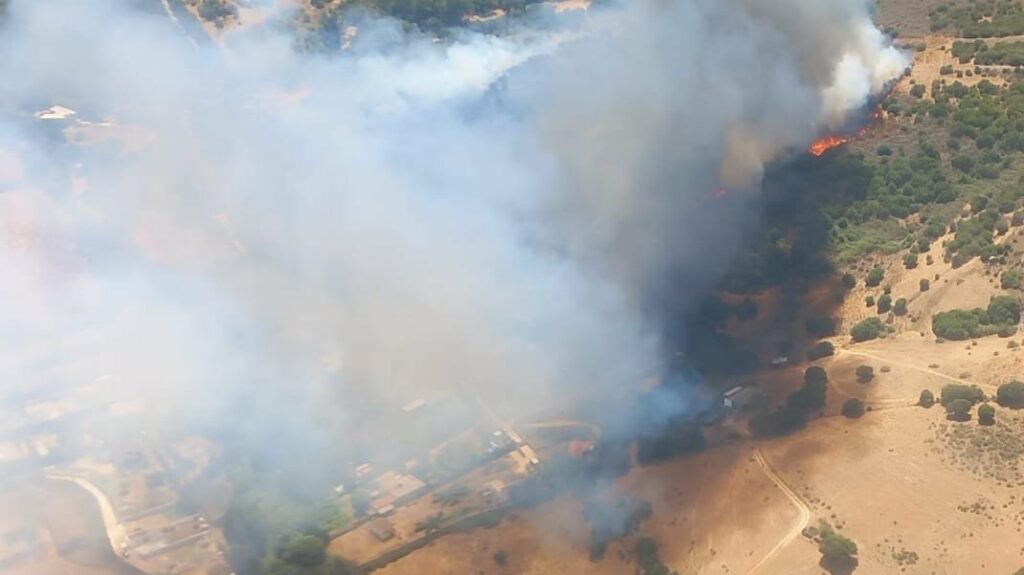 Vista aérea de una densa columna de humo y llamas producidas por un incendio forestal en San Roque, Cádiz, cerca de zonas habitadas.