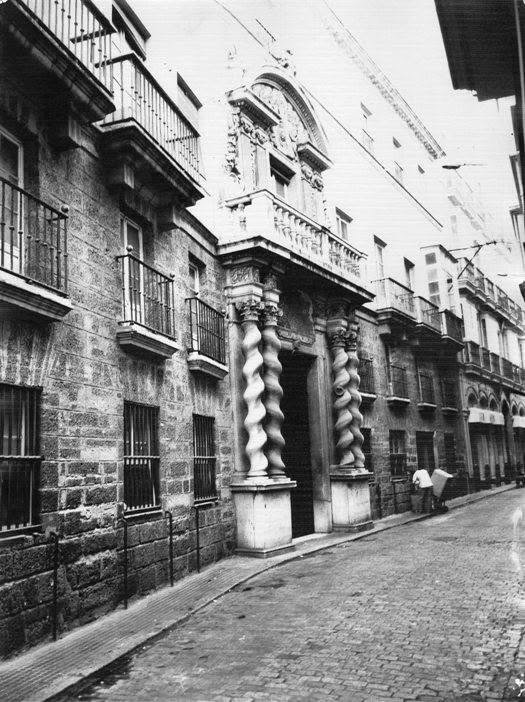 Fotografía en blanco y negro de la fachada de la Casa de las Cadenas en Cádiz con sus columnas salomónicas de mármol genovés en la portada barroca.