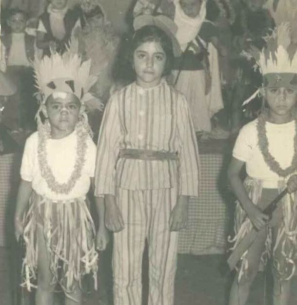 Fotografía en blanco y negro de los años 60 que muestra a tres niños disfrazados durante una actividad de la residencia de Cádiz. Dos de ellos llevan penachos de plumas y faldones de flecos simulando trajes tradicionales, mientras que el niño del centro viste un pijama de rayas.