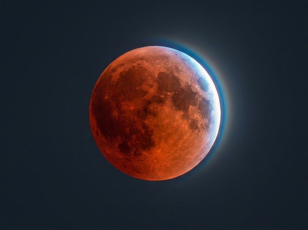 Primer plano en detalle del eclipse lunar del 28 de agosto con tonos rojizos y destello azul