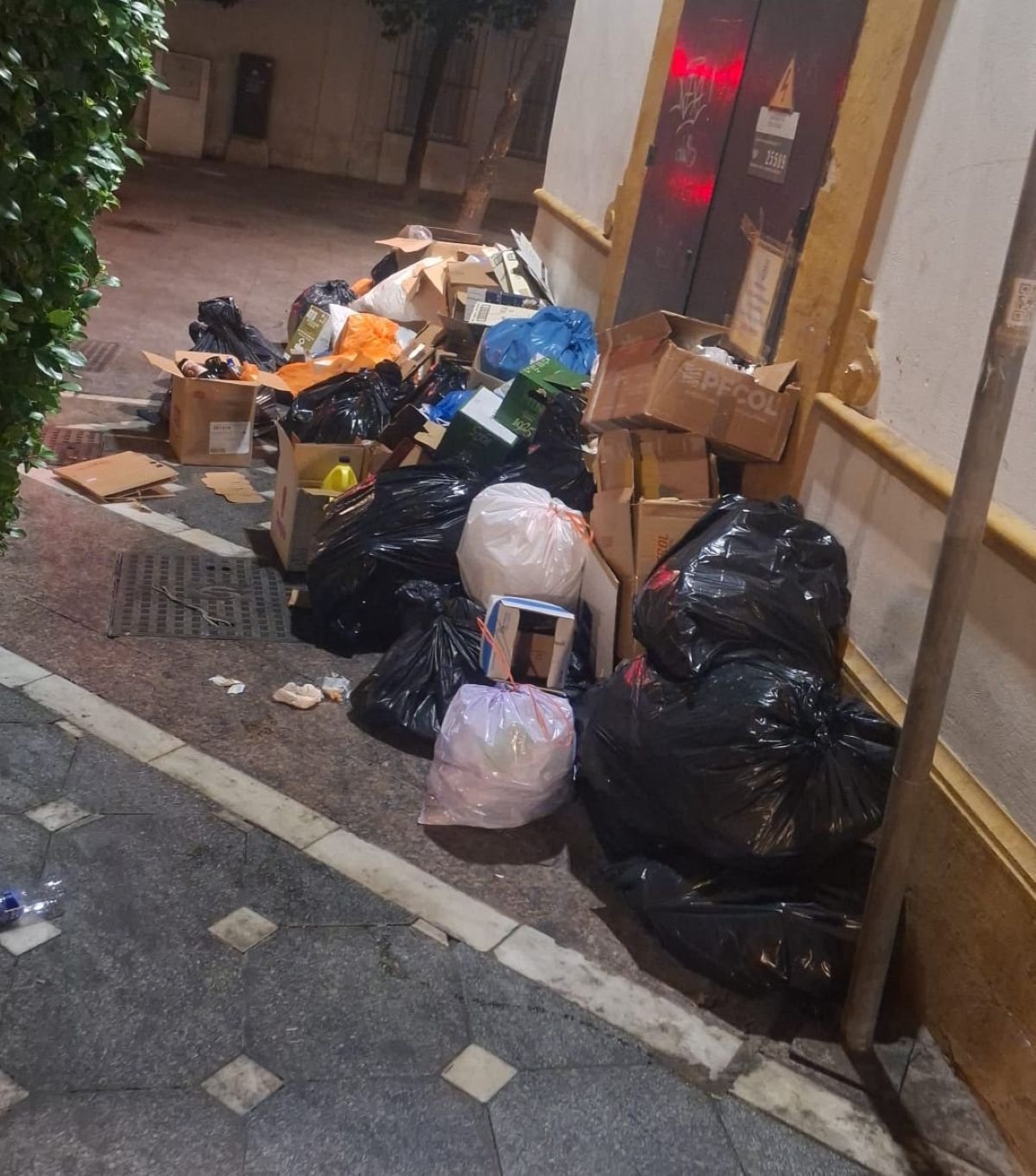 Gran acumulación de bolsas de basura y cajas de cartón apiladas sobre la acera en la esquina de las calles Belén y Padre Luis Bellido de Jerez.