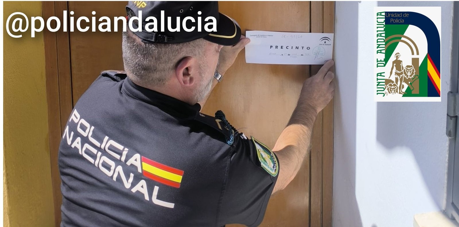Agente de la Policía Nacional Adscrita a Andalucía colocando un precinto oficial en la puerta de una vivienda turística clandestina en Sevilla.