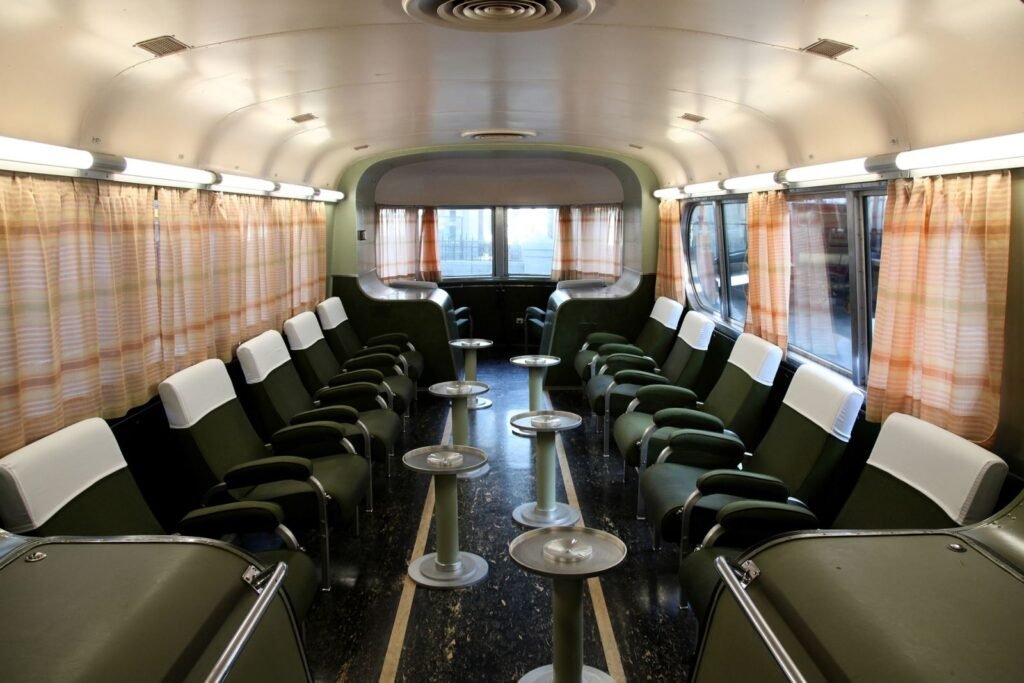 Vista interior restaurada de un coche de pasajeros del Talgo II con sus características mesas circulares y asientos originales.