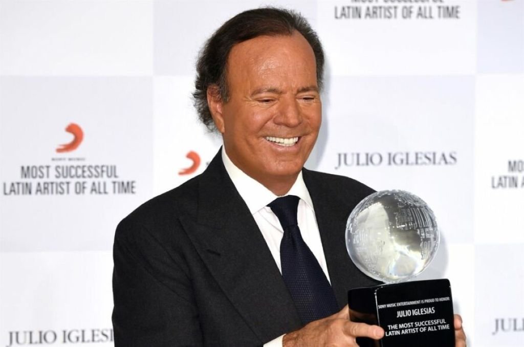 Julio Iglesias sonriente sosteniendo el trofeo de cristal de Sony Music al artista latino más exitoso de todos los tiempos.