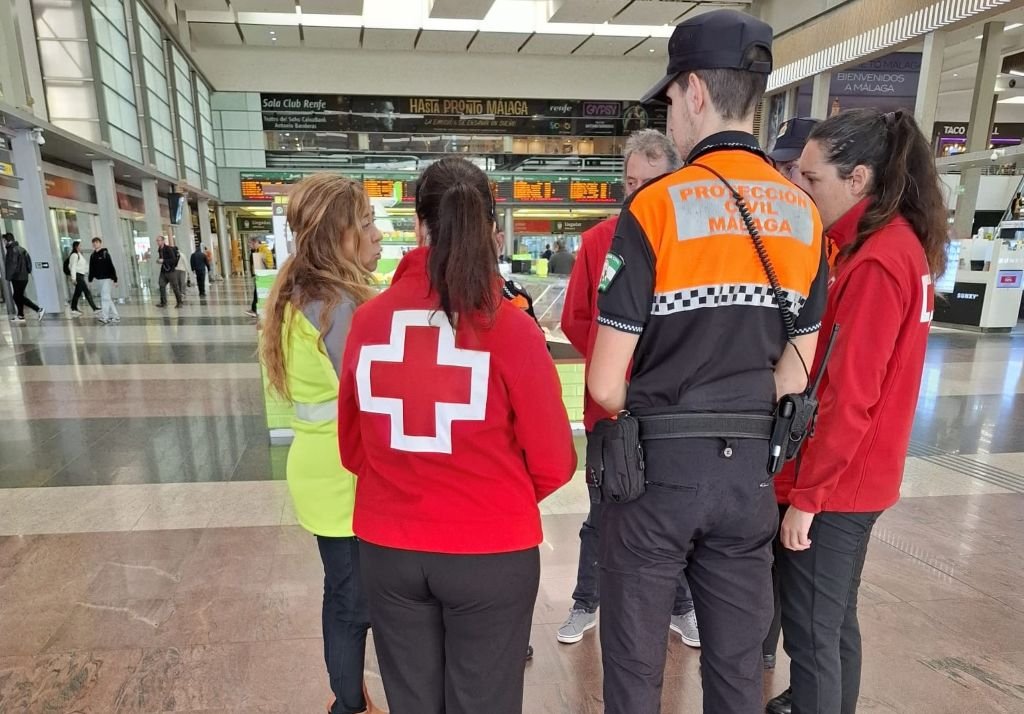 Voluntarios de Cruz Roja y Protección Civil de Málaga atendiendo a familiares en el interior de la Estación de Málaga María Zambrano.