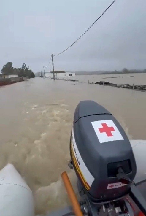 Motor de una lancha de Cruz Roja navegando por una carretera totalmente inundada en Jerez, con viviendas y postes eléctricos rodeados de agua.