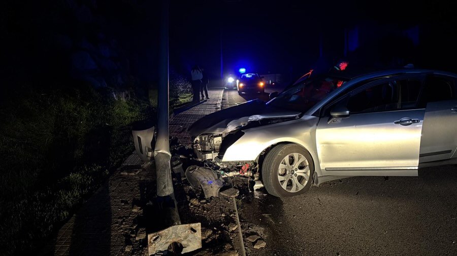 Vehículo plateado con graves daños frontales tras colisionar contra una farola en una actuación de la Policía Local de Medina Sidonia y seguridad vial durante la noche.