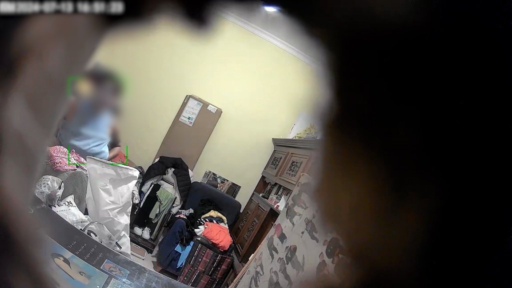 Captura de pantalla de una cámara oculta mostrando el interior de un dormitorio con ropa desordenada y un recuadro verde de detección de movimiento.