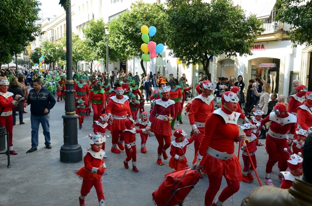 Pasacalles infantil de Carnaval en la calle Larga de Jerez con niños disfrazados de rojo.