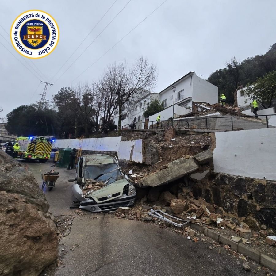 Coche Renault de color verde aplastado por los escombros de un muro tras un derrumbe en Ubrique.
