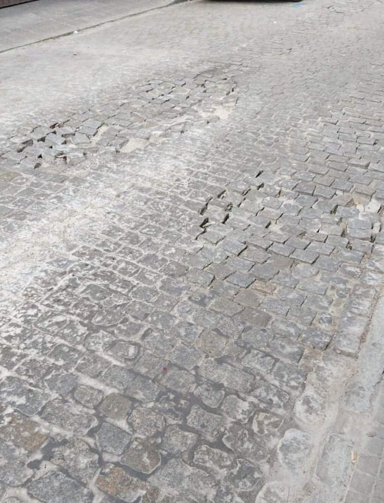Detalle de adoquines sueltos y desplazados formando baches peligrosos en la calzada de la calle Caballeros.