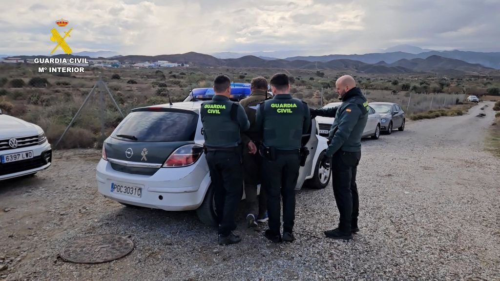 Agentes de la Guardia Civil escoltando a un detenido esposado hacia un vehículo patrulla en una zona rural de Almería.
