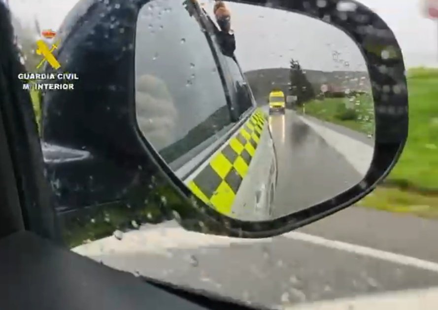 Guardia Civil escoltando una ambulancia en carretera bajo la lluvia durante un traslado sanitario urgente desde Ubrique.