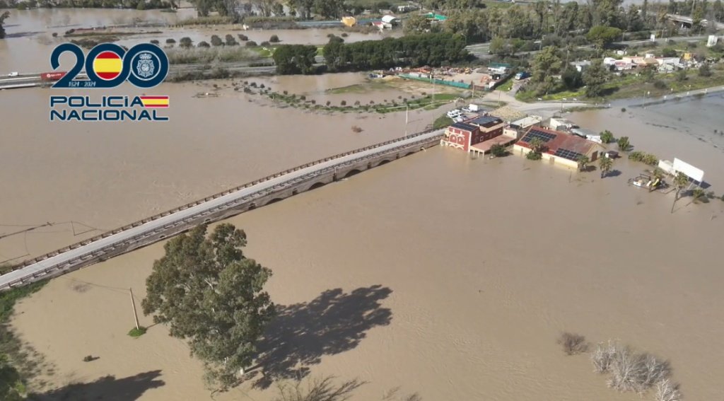Vista aérea desde helicóptero de la Policía Nacional sobre Jerez de la Frontera mostrando el desbordamiento del río Guadalete, viviendas inundadas en barriadas rurales y carreteras cortadas por el agua durante el temporal.