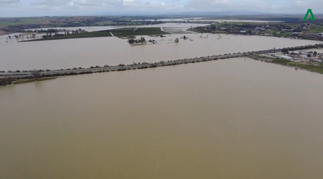 Fotografía aérea de las inundaciones en Jerez mostrando casas de la zona rural rodeadas por el desbordamiento del río Guadalete y campos anegados.