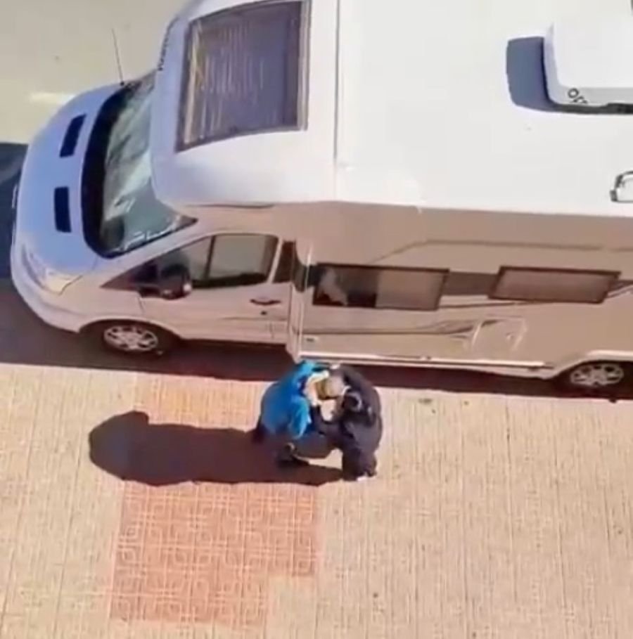 Fotograma del momento exacto de un robo por el método del abrazo a un hombre de avanzada edad junto a una autocaravana blanca.