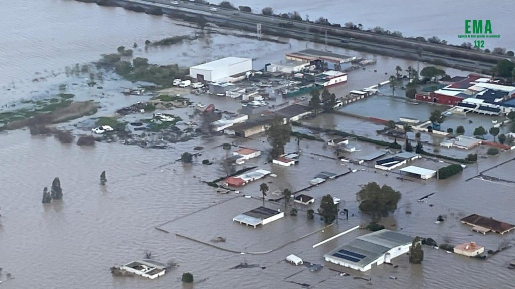 Vista aérea de una zona urbana e industrial totalmente anegada por el desbordamiento de cauces en Andalucía, bajo la coordinación de la Agencia de Emergencias EMA 112.