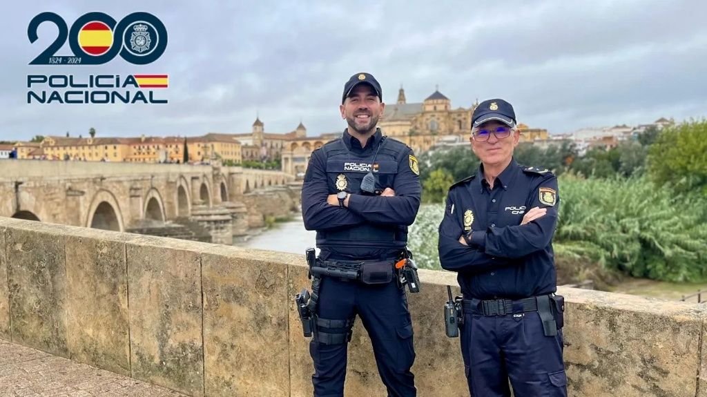 Dos agentes de la Policía Nacional posan en el Puente Romano de Córdoba con la Mezquita-Catedral al fondo, imagen representativa de la seguridad en la ciudad tras los incidentes en el Sector Sur.