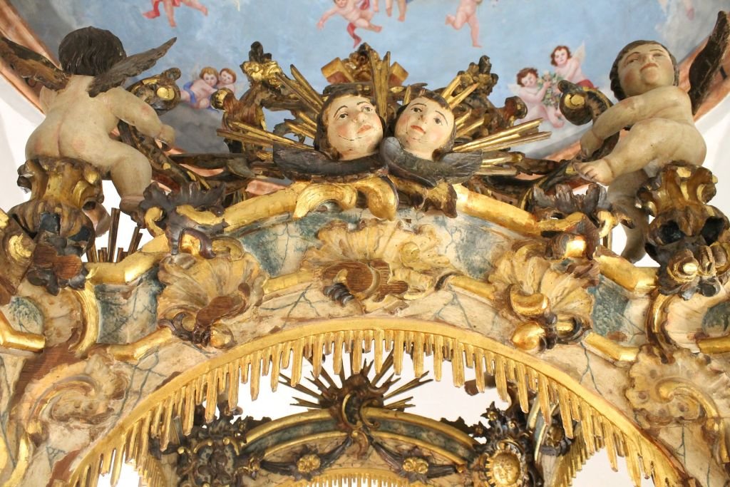 Primer plano del proceso de restauración del tallado dorado donde se aprecian las pinceladas y la técnica de consolidación del oro original.