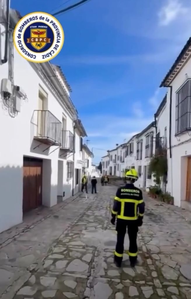 Bomberos del Consorcio de Cádiz supervisando la vuelta a casa de vecinos de Grazalema en una calle empedrada tras el temporal.