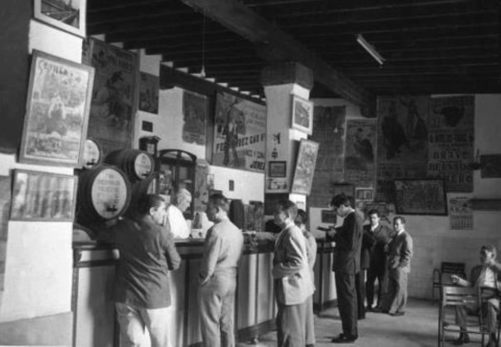 Fotografía antigua en blanco y negro del interior del Tabanco San Pablo con clientes en el mostrador