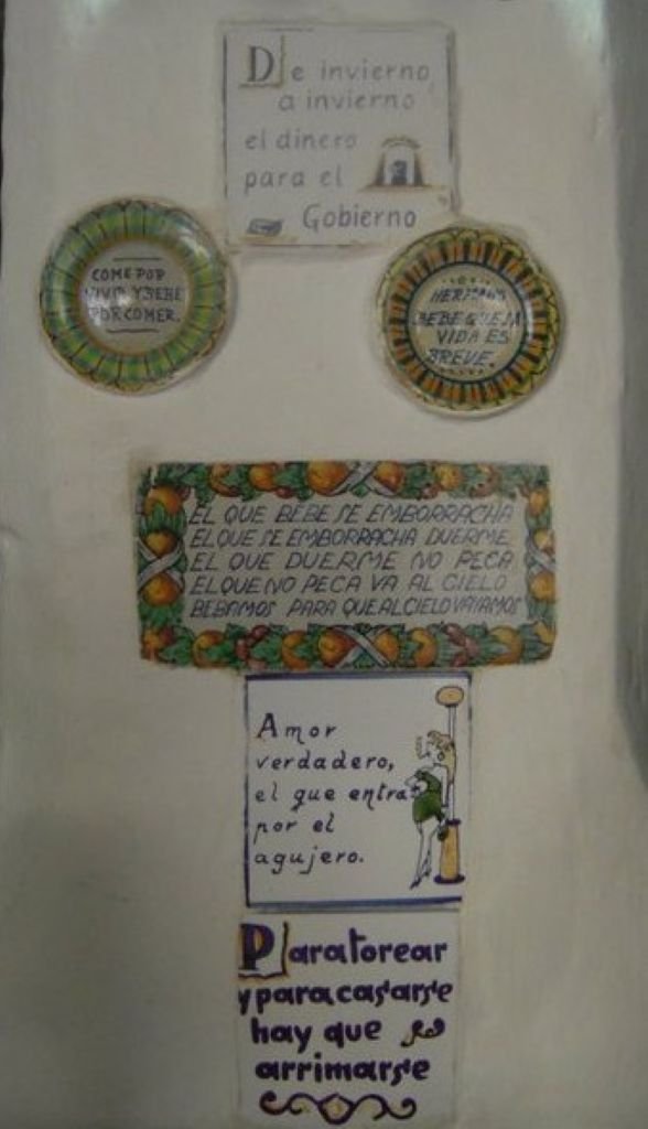Pared con azulejos decorativos y platos de cerámica con refranes populares sobre el vino y la vida en Jerez