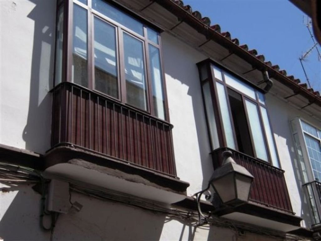 Primer plano de balcones de madera y cristal típicos de la arquitectura civil de Jerez bajo un cielo azul.