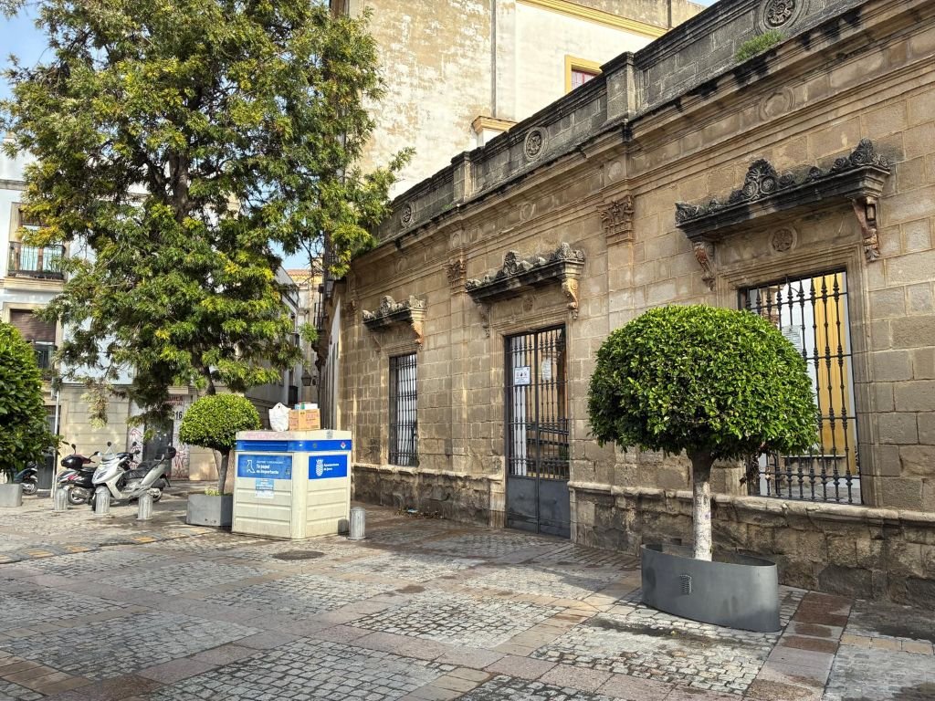 Plaza del Progreso en Jerez de día con un único contenedor de papel y cartón junto a un parque.