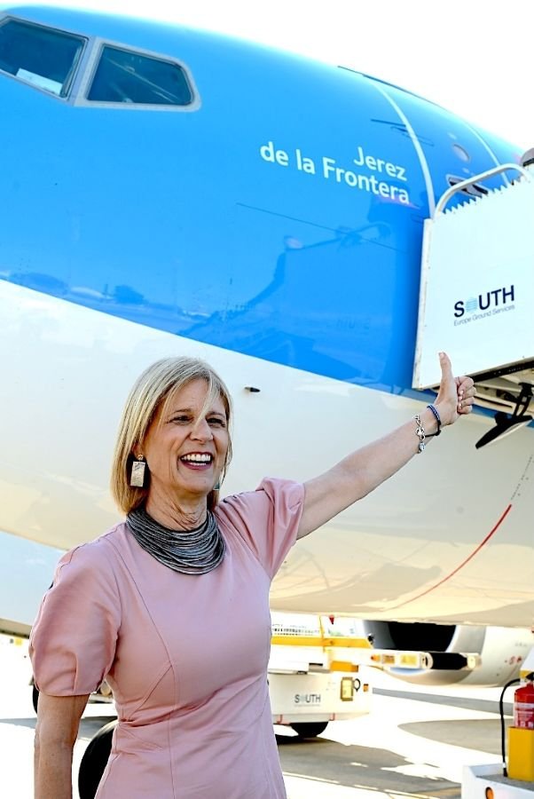 María José García-Pelayo sonríe y señala con el pulgar hacia arriba el nombre de Jerez de la Frontera impreso en el fuselaje azul del avión Boeing 737 de TUI durante el bautizo en el aeropuerto.