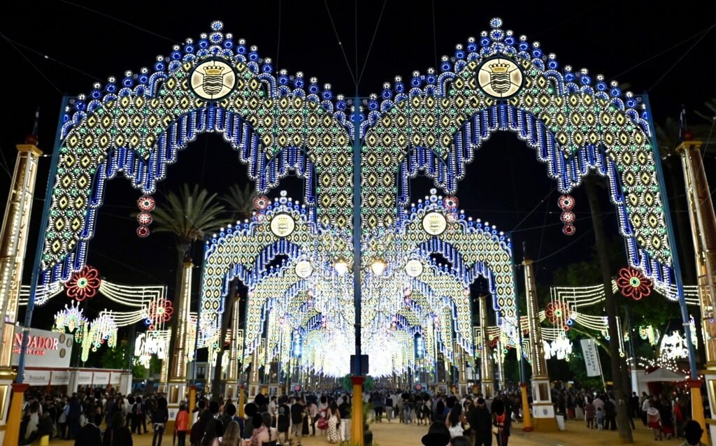 Perspectiva nocturna de los arcos de luces azules y amarillas en el Real de la Feria de Jerez.