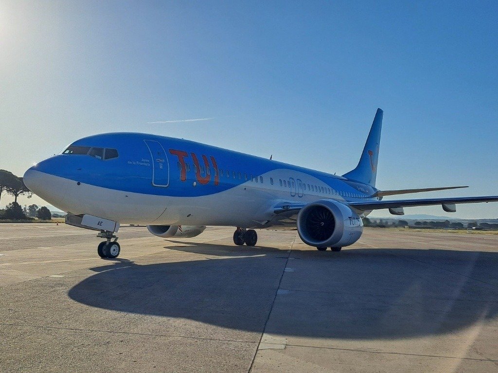 Plano general de perfil del avión Boeing 737 MAX 8 de la compañía TUI con su característico color azul estacionado en la pista del Aeropuerto de Jerez bajo un cielo despejado.