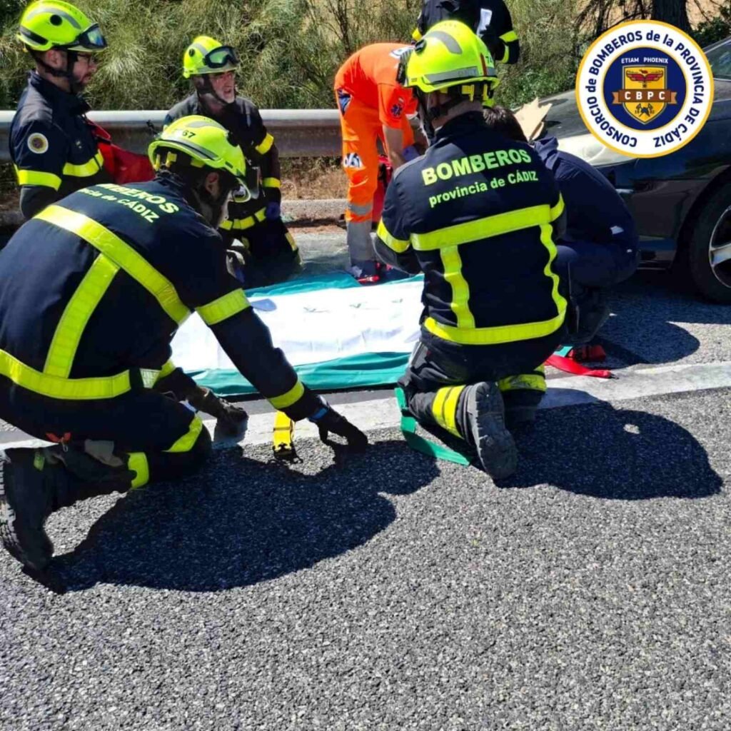 Efectivos del Consorcio de Bomberos de Cádiz y sanitarios atendiendo a una víctima en el suelo de la calzada de la AP-4.