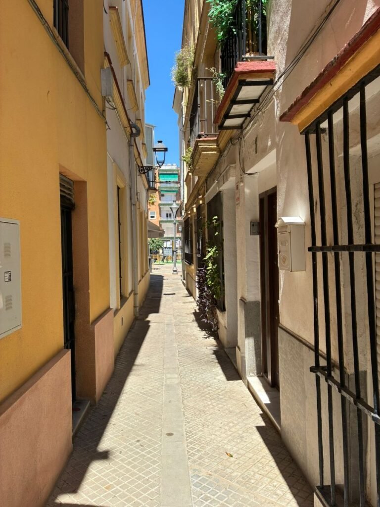 Vista panorámica de la calle Nogal en Jerez, mostrando su estrechez característica y su desembocadura hacia la plaza del Progreso.