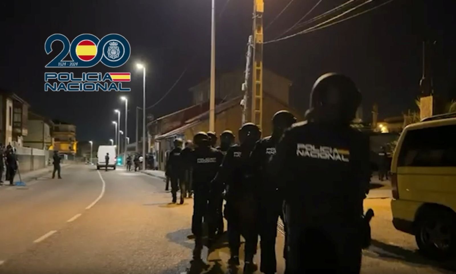 Agentes de la Policía Nacional avanzan en fila por una calle de noche durante el macrooperativo policial en Torrelavega.