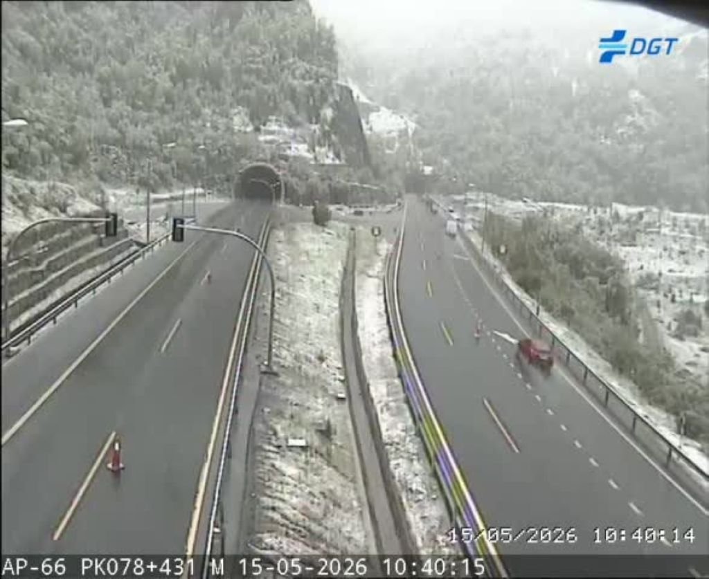 Captura de cámara de tráfico de la DGT en la autopista AP-66 el 15 de mayo de 2026, mostrando la calzada mojada y los márgenes cubiertos de nieve junto a la entrada de un túnel.