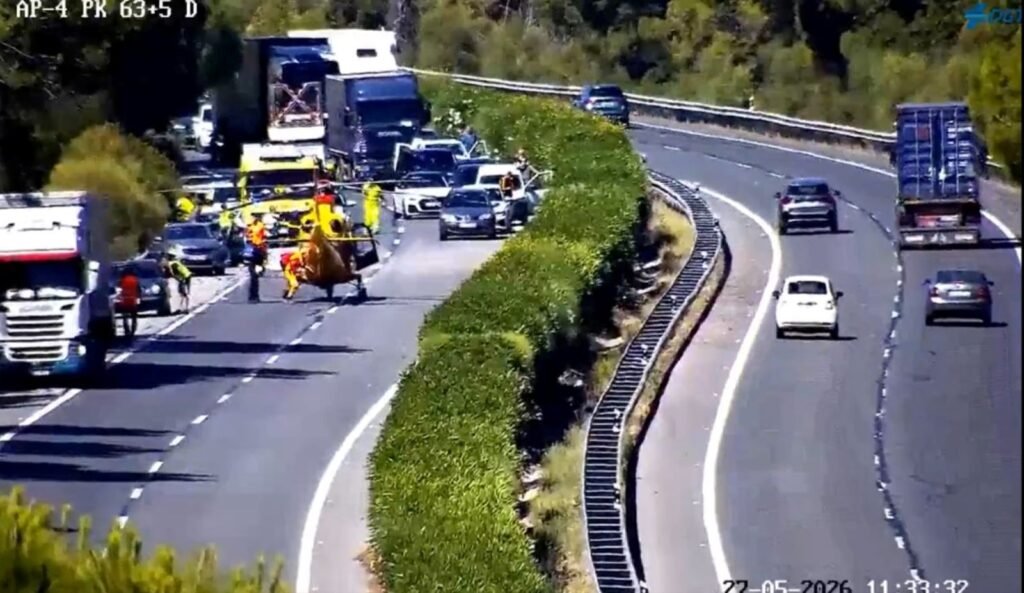 Helicóptero de emergencias sanitarias aterrizado en mitad de la autopista AP-4 a la altura de El Cuervo junto a coches retenidos, camiones y personal de rescate tras un grave accidente de tráfico.