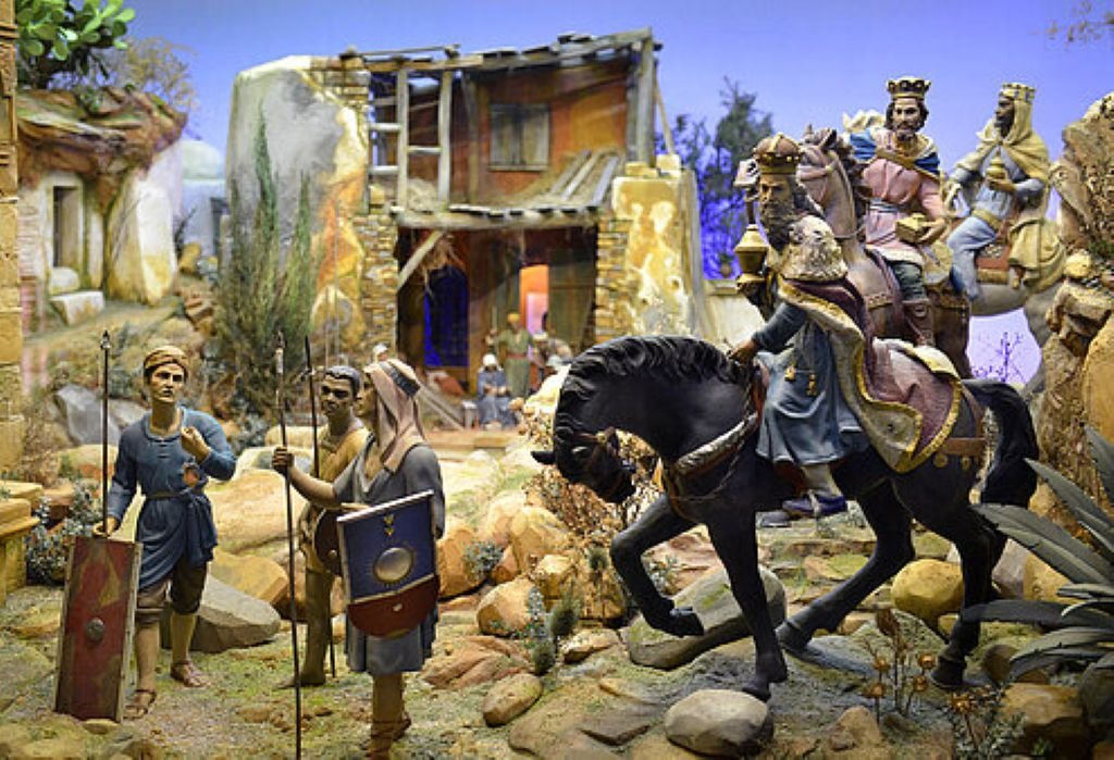 Recreación de la llegada de los Reyes Magos a caballo y camello custodiados por soldados con escudos.