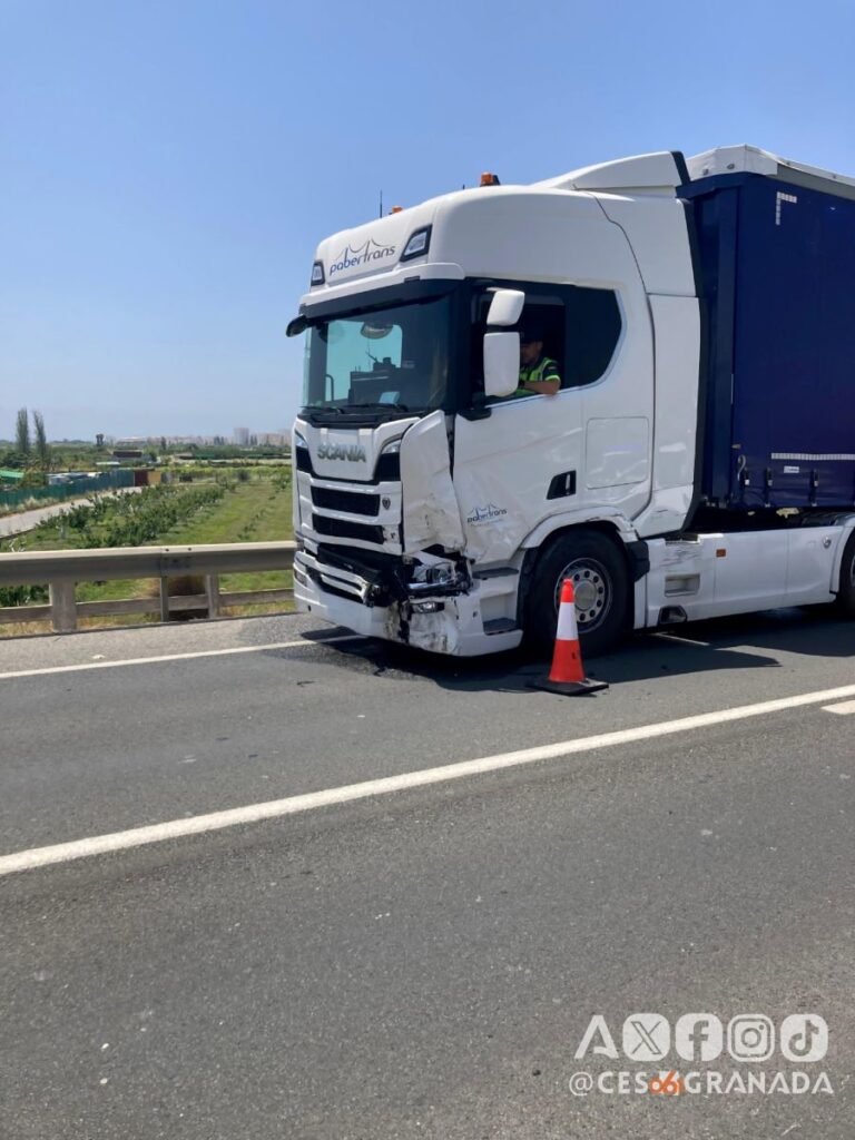 Parte delantera izquierda abollada de un camión blanco de la empresa Pabertrans parado en el arcén con un cono de seguridad vial tras el accidente de trafico en Salobreña.