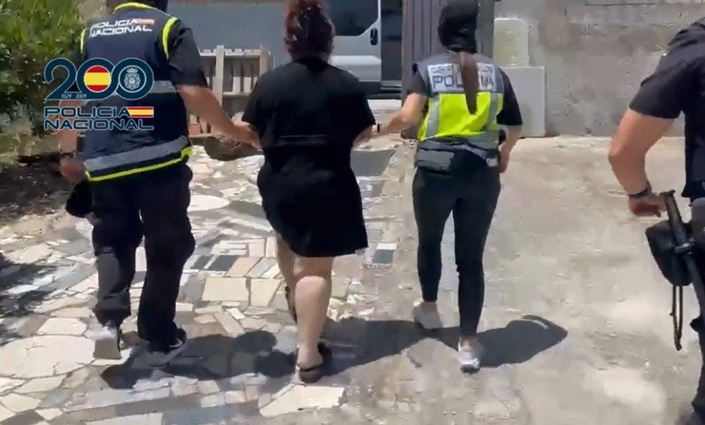 Agentes de la Policía Nacional escoltan a una de las detenidas durante el operativo de desarticulación de la red de trata de seres humanos en Andalucía.