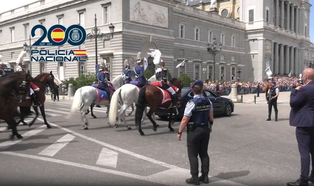Guardia Real y escolta a caballo acompañan a un vehículo oficial negro frente a la Catedral de la Almudena y el Palacio Real de Madrid.