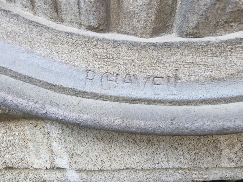 Primer plano de la firma grabada en piedra esculpida que reza R. CHAVELI en la base del medallón del Ayuntamiento de Jerez.